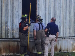 Deputy Coroner Ken Franklin (right) looks over the scene with fire officials. Two people were pulled from the mobile home. Their names and conditions have not been released.